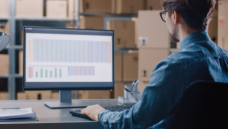 DHL Shipping and Magento 2: Man at a computer in a warehouse